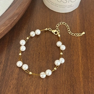 Bracelet élégant à double rang de perles dorées avec fermoir ajustable sur du bois