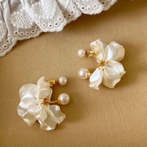 Elegante weiße Perlenohrringe in Blütenform mit goldenen Details auf beigem Hintergrund
