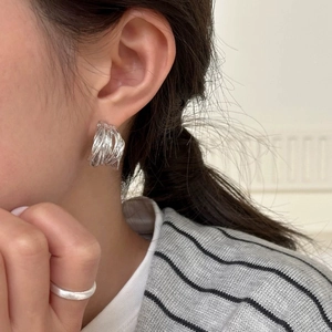 Détail des boucles d'oreilles irrégulières en métal liquide argenté sur modèle