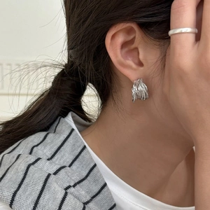 Gros plan détaillé des boucles d'oreilles argentées en C et de la bague minimaliste