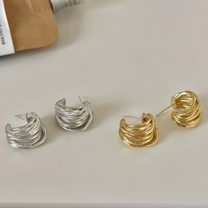Gros plan sur d'élégantes boucles d'oreilles en C multicouches en or et argent