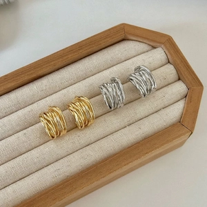 Détail de boucles d'oreilles créoles dorées et argentées multicouches sur plateau velours