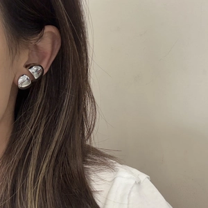 Minimalist silver spherical ear cuff with a polished mirror finish worn by a model