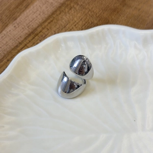 Detailed view of wide minimalist silver-colored metal ring on white ceramic plate