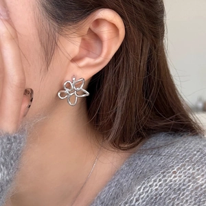 Gros plan de boucles d'oreilles fleurs évidées en argent portées pour un style moderne