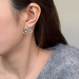 Vue macro d'un clou d'oreille fleur argentée évidée sur mannequin au style épuré