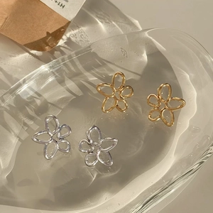 Vue détaillée des boucles d'oreilles fleurs ajourées en or et argent sur un plateau