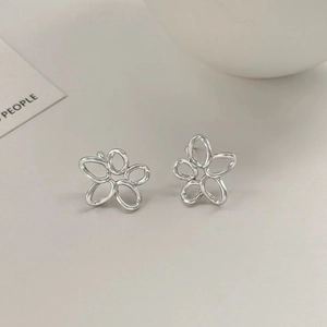 Détail de boucles d'oreilles minimalistes en forme de fleur évidée argentée