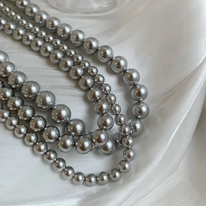 Macro shot of multi-layer metallic silver pearl necklace on elegant white silk background