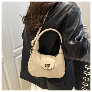 Detail of off-white patent leather dumpling bag with gold lock and rigid round handle