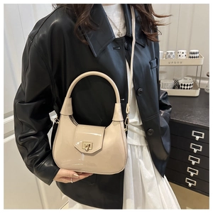 Close-up of beige patent leather dumpling bag with gold twist lock and round handle