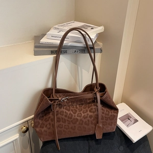 Large leopard print tote bag with buckle detail on a chair in a cozy home setting