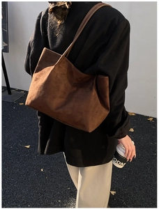 Detail view of large dark brown suede tote bag worn by a model for daily commute