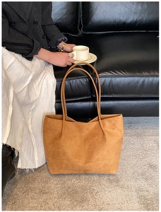 Detailed view of spacious caramel suede tote bag with slim shoulder straps on grey rug