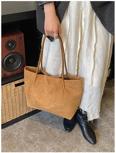 Macro view of textured brown suede tote bag with slim handles in a lifestyle setting