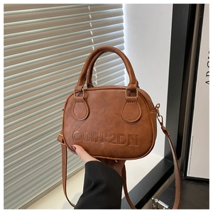 Détail d'un sac Boston rétro en cuir marron avec logo embossé et finitions dorées