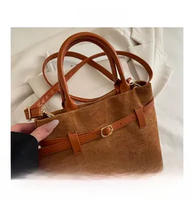 Détail du sac seau vintage en daim marron avec boucle dorée et bandoulière réglable