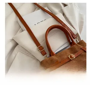 Gros plan détaillé d'un sac seau mat marron avec boucle dorée réglable et bandoulière