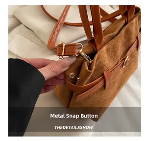 Gros plan sur le bouton-pression doré et la texture en daim du sac à main marron
