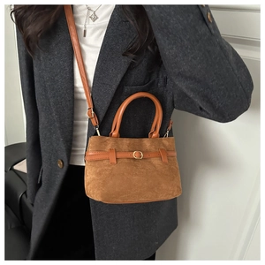 Détail du sac seau en daim marron avec bandoulière en cuir et boucle métallique dorée