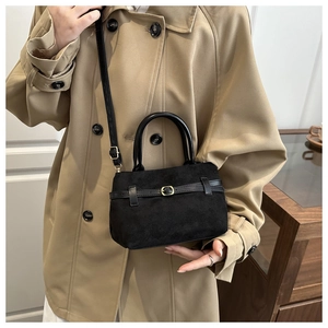 Détail d'un sac seau noir mat en daim avec boucle de ceinture et bandoulière réglable