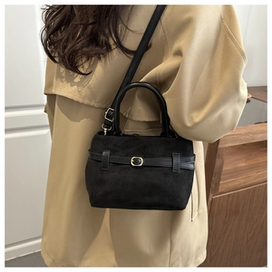 Sac seau en daim noir tendance avec boucle décorative porté par un mannequin