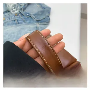 Detail of caramel brown PU leather handbag with yellow contrast stitching and top handle