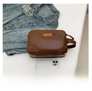 Detail of dark brown leather makeup bag with contrast stitching and top handle