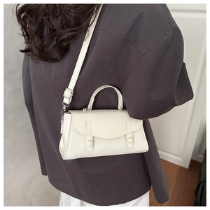 Rear view of model wearing a stylish white leather crossbody bag with dual round buckles