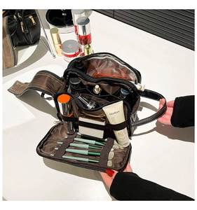 Detail view of the multi-compartment interior and brush slots of a black leather makeup bag