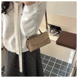 Close-up of a chic beige crossbody bag shown on a model in a cozy lifestyle setting
