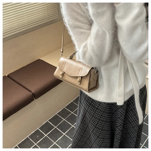 Detail of khaki retro square bag with decorative round buckles and slim shoulder strap