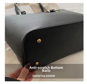 Dettaglio della borsa tote in pelle Saffiano nera con piedini protettivi dorati sul fondo