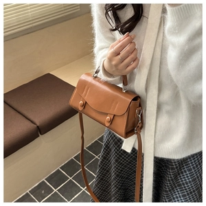 Brown vintage faux leather square bag shown in a lifestyle cafe setting with soft lighting