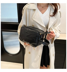 Close-up of black leather clutch with white contrast stitching and side handle grip