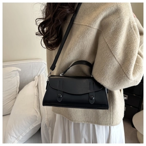 Detail showing matte black crossbody bag with decorative buttons and silver hardware