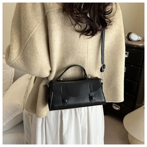 Model wearing a chic black crossbody square bag in a cozy indoor setting, side view detail