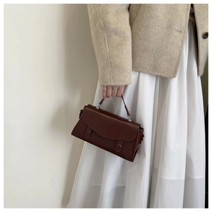 Detail of a dark brown vintage mini handbag featuring decorative double buckle straps