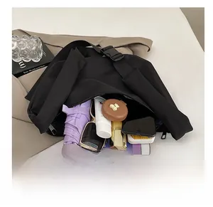 Top view of spacious interior of black messenger bag with tablet, umbrella and makeup