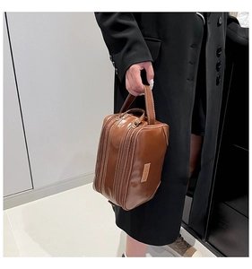 Detailed macro view of the brown leather vanity case showing double zippers and side handle