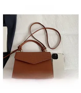 Detail of brown crocodile pattern small crossbody bag with knotted handle and smartphone