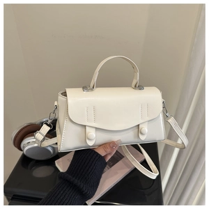 Detail view of cream white handbag with unique stitching and dual cylindrical buckles