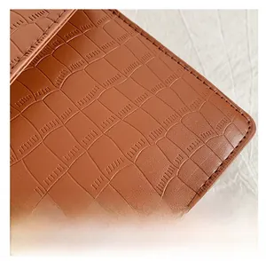 Macro shot of brown crocodile embossed leather texture with fine stitching on a bag