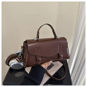 Close-up of a vintage brown leather crossbody bag with structured flap and top handle