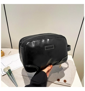 Close-up of black leather makeup bag with litchi texture and multi-zipper design