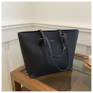 Dettaglio della borsa tote nera in ecopelle con elegante logo dorato sulla parte frontale
