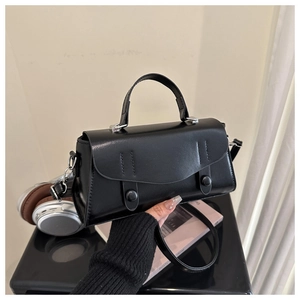 Close-up of black vintage rectangle bag with smooth faux leather and dual button detail
