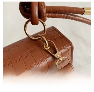 Close-up of brown crocodile texture leather bag with gold metal ring and detachable hook