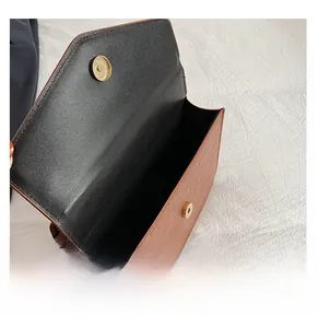 Macro view of the internal opening and magnetic gold buckle of the brown textured bag