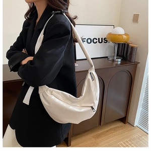 Close-up of off-white hobo bag with adjustable wide strap and metallic zipper detail